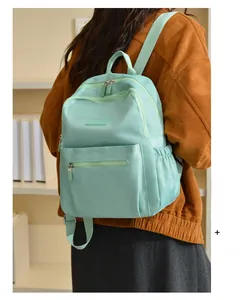 Detail view of a mint green nylon backpack with multi-layer zippers and side pockets