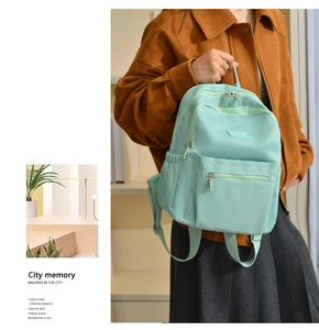Detail view of mint green nylon backpack with multiple pockets and side water bottle holder