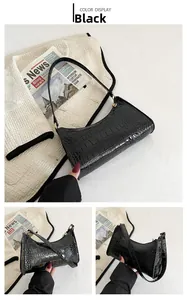 Detailed view of black crocodile pattern baguette bag with adjustable leather shoulder strap