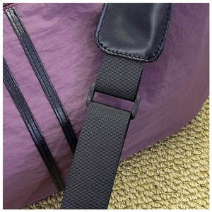 Detailed macro view of purple waterproof nylon fabric and reinforced black strap stitching