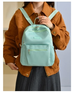 Detailed front view of a mint green nylon backpack showing premium texture and zipper pockets