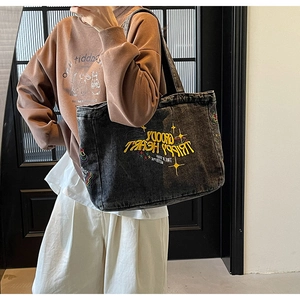 Détail d'un grand sac cabas en denim lavé avec broderie jaune et motifs d'étoiles