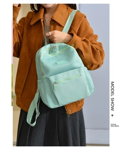 Detail view of mint green nylon backpack showing water-resistant fabric and side pockets
