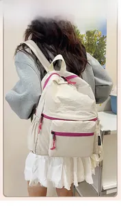 Close-up of cream nylon backpack featuring vibrant pink zippers and lightweight fabric