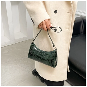 Dark green crocodile pattern faux leather shoulder bag held by a model in a beige coat