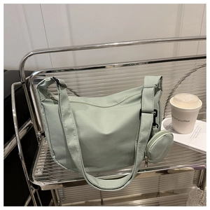 Close-up of light green nylon crossbody bag with grid texture and small round coin purse