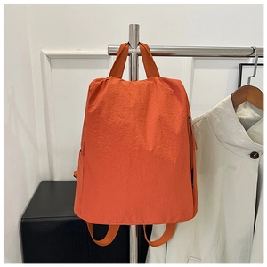 Detailed view of bright orange nylon backpack with minimalist design and wide handles