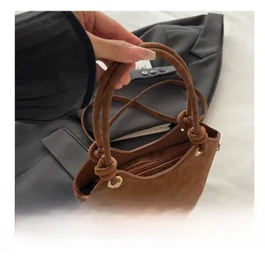 Détail d'un sac cabas marron souple avec poignée nouée et fermeture éclair dorée de qualité