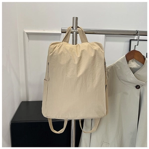 Detail view of a beige nylon backpack hanging on a rack with adjustable straps
