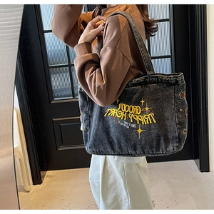 Gros plan détaillé du sac cabas en denim vintage montrant les broderies d'étoiles colorées