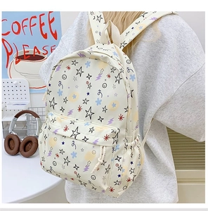 Detail view of cream backpack featuring colorful star patterns and multi-pocket design