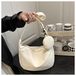 Detail of off-white crescent crossbody bag with mini round coin purse and adjustable strap
