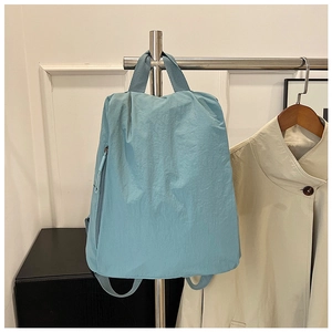 Detail of light blue nylon backpack showing the vertical zipper pocket and webbing handle