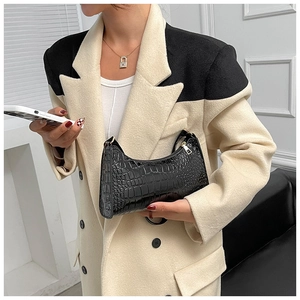Close-up of black crocodile-embossed crescent handbag with elegant gold hardware