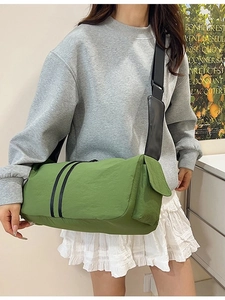 Green nylon cylindrical crossbody yoga bag with adjustable black strap and side pocket