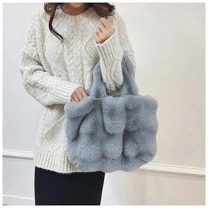 Détail du sac à main en peluche grise avec oreilles de lapin porté sur un pull en maille