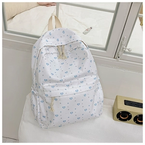 Close-up of white canvas backpack with blue heart patterns and woven rope zipper detail
