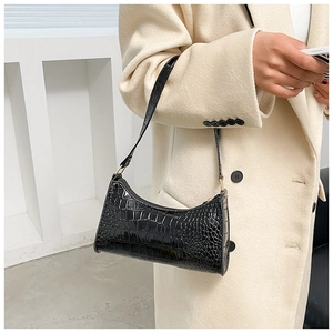 Detail of black faux crocodile leather shoulder bag with glossy texture and metal hardware
