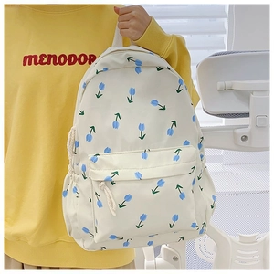 Detail view of white canvas backpack featuring blue tulip floral print and front zipper pocket