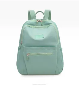 Front view of light green waterproof nylon backpack with zipper pockets and branding