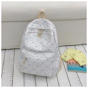 Detail shot of a white canvas student backpack with blue heart and star patterns