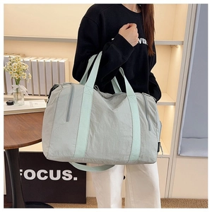 Detail of grey nylon travel bag with mint green straps and side zipper pocket