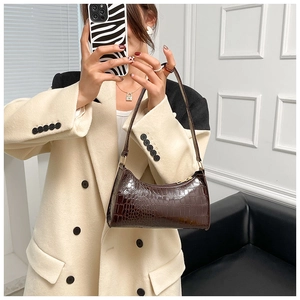 Detail of dark brown faux crocodile leather baguette bag with metal zipper and slim strap