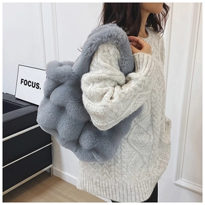Gros plan du sac fourre-tout en fausse fourrure bleu-gris et pull en maille blanc