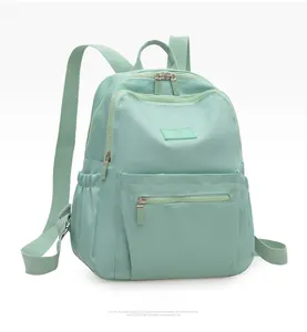 Detail view of mint green nylon backpack with front zipper pocket and multiple compartments