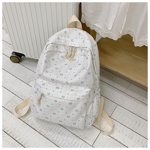 Close-up of white canvas backpack with blue heart and grey star prints and front pocket