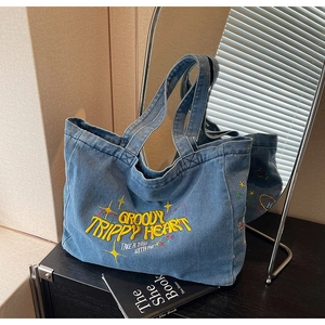 Gros plan détaillé du sac cabas en denim bleu avec broderie Groovy Trippy Heart jaune