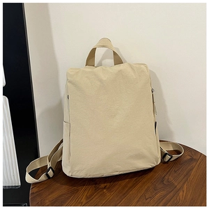 Detail view of adjustable nylon straps and side pockets on beige backpack