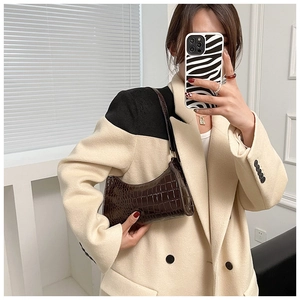 Close-up of dark brown crocodile embossed leather shoulder bag with chic curved silhouette
