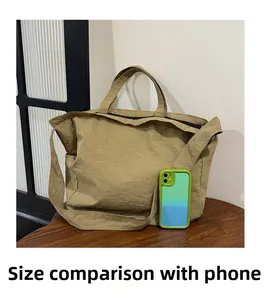 Close-up of khaki canvas tote bag comparing its large capacity size to a smartphone