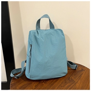 Detail view of water-resistant light blue nylon backpack on a dark wood table