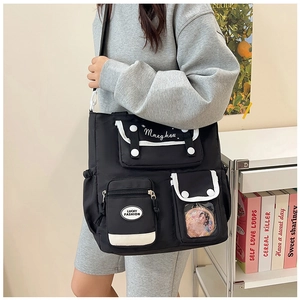 Detail view of black multi-pocket nylon shoulder bag with white contrast piping on a model