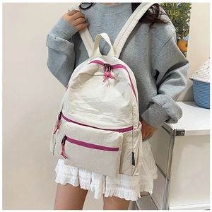 Detail view of cream casual backpack with contrast pink zippers and multiple pockets