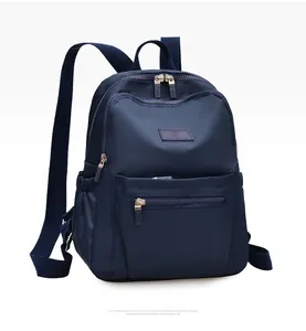 Detail of dark blue nylon backpack showing layered zipper design and side storage pocket