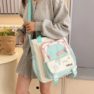 Detail view of multi-pocket canvas tote bag with adjustable strap in mint green and beige