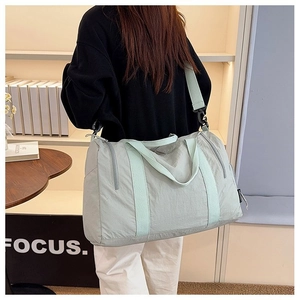 Detail of mint green nylon travel bag showing adjustable shoulder strap and side zipper pocket