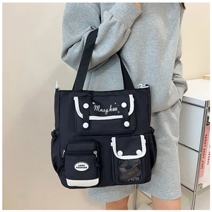 Detail of a black nylon tote bag with multi-pockets and contrast white trim
