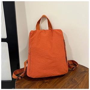 Detail view of bright orange nylon backpack with textured fabric and durable straps