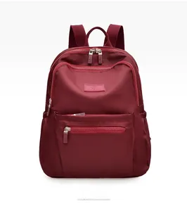 Front view of a burgundy nylon backpack with double zippers and multiple pockets