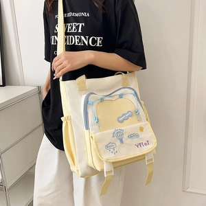 Detail view of canvas tote bag with Happy Days embroidery and clear mesh pocket on front