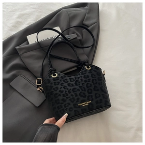 Detailed view of leopard print bucket bag with gold hardware and logo on white fabric