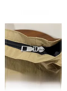 Detailed close-up of the smooth metal zipper and stitching on the khaki canvas tote bag