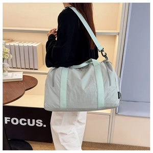 Detail of mint green nylon gym bag with adjustable shoulder strap and side zipper pockets