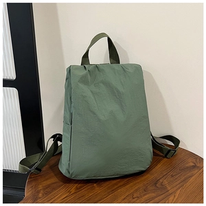 Detailed view of army green nylon backpack with top handle on a wooden surface