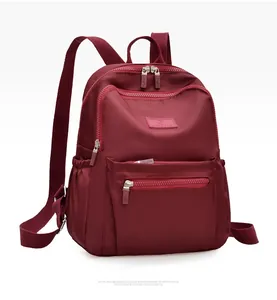 Detailed side view of a wine red waterproof nylon backpack with multiple zipper pockets
