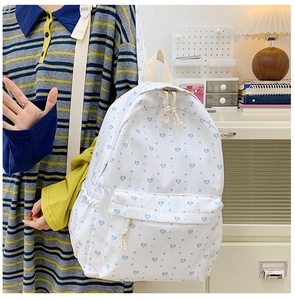 Detail showing white canvas backpack with blue heart prints and cord zip pullers